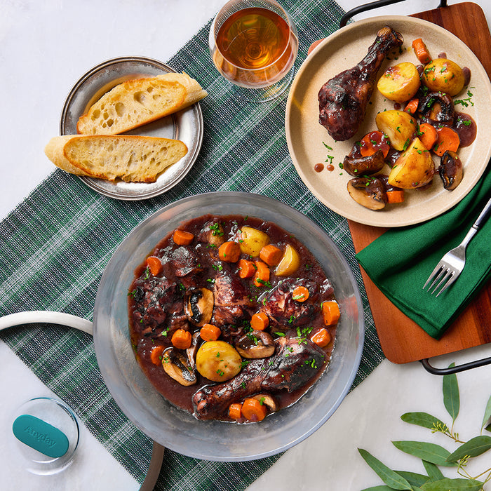 Enjoy a hearty and delicious meal by serving coq au vin with potatoes, carrots, and mushrooms in the 12-Cup Glass Round Deep Dish, paired with sliced bread and a glass of wine on a green plaid tablecloth—ideal for meal-prepping or feeding a crowd.