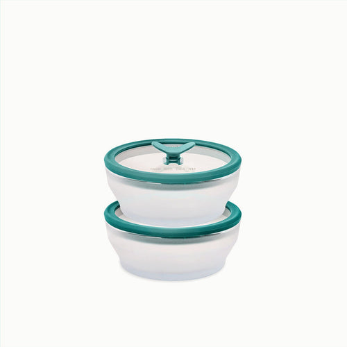 Two glass round dishes, each with a 2-cup capacity, are stacked on top of each other against a white background. Ideal for storing leftovers, the top dish features a clear glass base and is topped with a teal lid that has a triangular handle in the center.