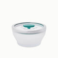 The 4-Cup Glass Round Deep Dish features frosted glass construction with a clear lid and a teal circular vent in the center, making it ideal for steaming vegetables or reheating leftovers in the microwave; shown on a white background.