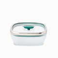 The 5.5-Cup Glass Square Shallow Dish is a transparent, square-shaped food storage container ideal for steaming asparagus in the microwave. It comes with a green-tinted, airtight lid accented by a silver rim and a dark green center tab.