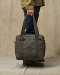 Person holding a green bag against a beige background