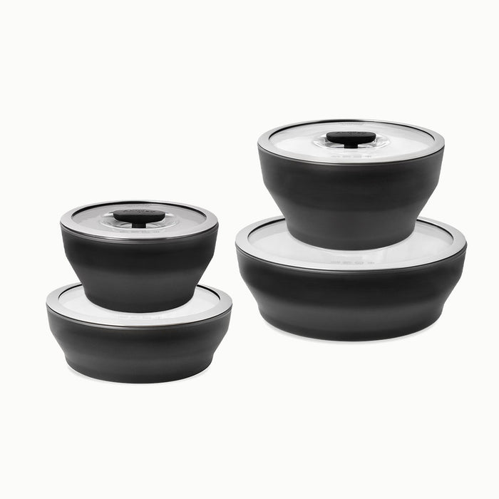 Four black, round Onyx Collection food storage containers for microwave meals, each with a white transparent lid, arranged in two stacks of two containers against a white background. These limited-edition Onyx Collection containers blend practical function with modern design.
